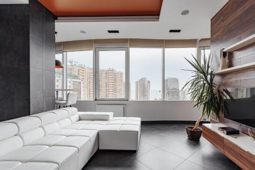 una sala de estar con un gran sofá blanco y grandes ventanas en Royal Apartment, en Odessa