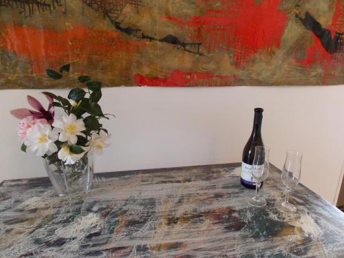 a bottle of wine and a vase of flowers on a table at Antica Dimora del Portico in Borgiallo