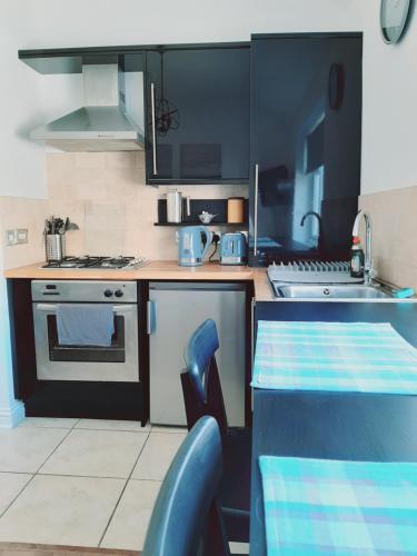 a kitchen with black cabinets and a table with chairs at Cosy 1 Bedroom Apartment in the Heart of Llandudno in Llandudno