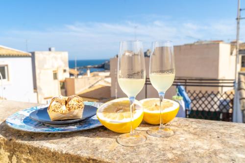 two glasses of white wine and a plate of lemons at VICOLO A MARE in Siracusa