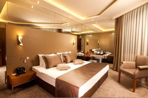 una camera d'albergo con un grande letto e una sedia di MAJURA HOTEL BUSINESS a Karşıyaka