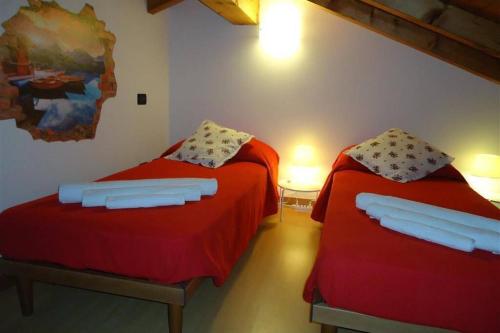 two beds in a room with red sheets at Piscina e vistalago CroceMenaggio CIR 013145-00318 in Menaggio