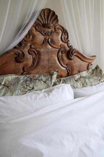 a bed with a wooden headboard and white sheets at RiverSide Suite - Haarlem City Centre in Haarlem