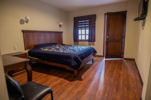 a bedroom with a bed and a desk and a window at Suites & Hotel El Quijote in Cuenca