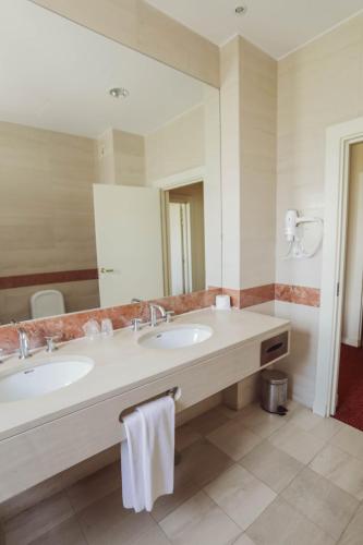 a bathroom with two sinks and a large mirror at Hotel Termas da Curia in Curia