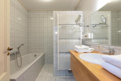 uma casa de banho com uma banheira, um lavatório e um chuveiro em Hotel de Watermölle em Haaksbergen