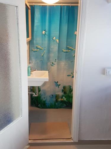 a bathroom with a fish shower curtain with a sink at Sole...Mare...e...Spiaggie Bianche! in Vada