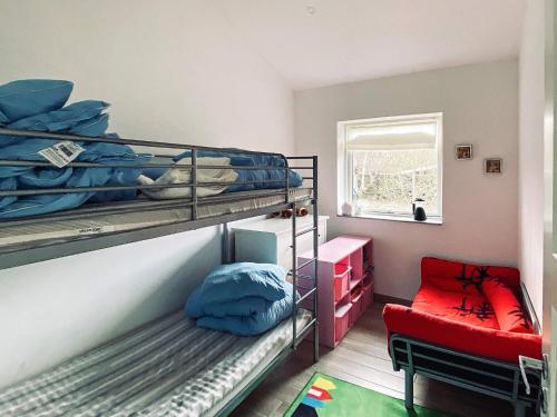 a room with two bunk beds and a red chair at 7 person holiday home in Jægerspris-By Traum in Jægerspris
