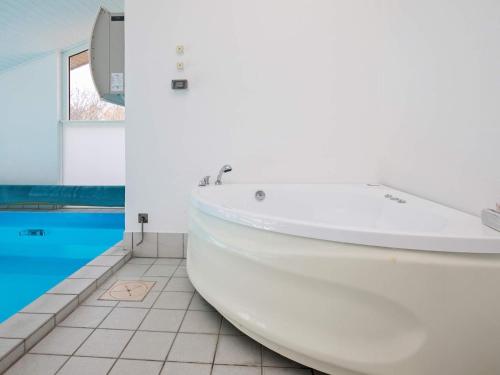 a white bath tub in a bathroom with a pool at Four-Bedroom Holiday home in Fjerritslev 3 in Torup Strand