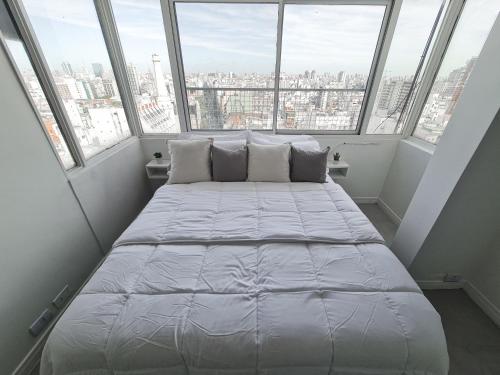 1 cama grande en una habitación con ventanas grandes en G&G Apartments - Recoleta City View en Buenos Aires