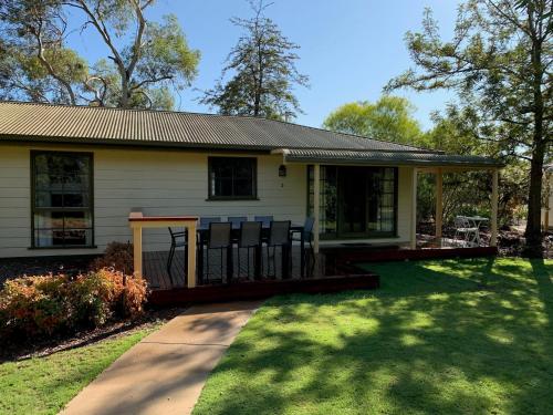 a small white house with a porch and a yard at Winbi River Resort Holiday Rentals in Moama