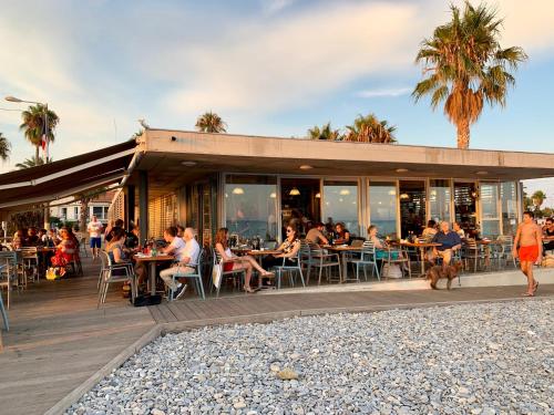 カーニュ・シュル・メールにあるFrench Riviera Deluxe near Nice airportのビーチ沿いのレストランで、テーブル席に座る人々と一緒に食事をする