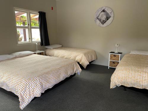 a bedroom with two beds and a clock on the wall at Twizel Holiday Park in Twizel