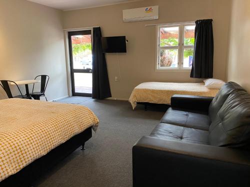 a hotel room with a couch and a bed and a window at Twizel Holiday Park in Twizel