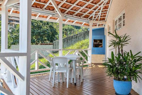 un porche con una mesa blanca y sillas. en Casas com jacuzzi e churrasqueira a 500 metros da Praia do Perequê na Ilhabela, en Ilhabela