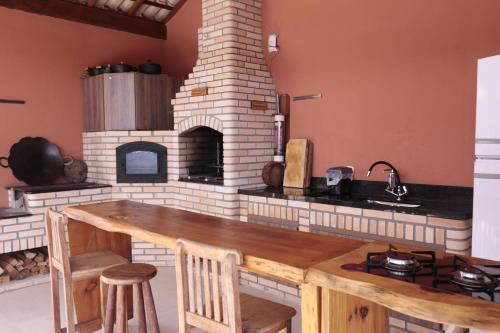 a kitchen with a brick oven with a wooden table at Repouso Mantiqueira in Santo Antônio do Pinhal
