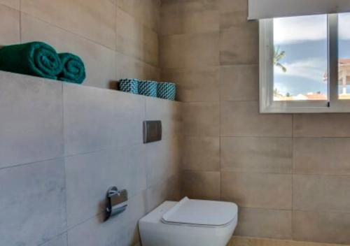 a bathroom with a white toilet and a window at Apartamento Deluxe para Parejas en Punta Cana in Punta Cana