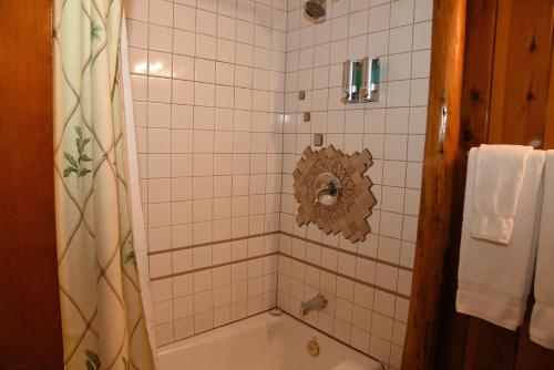 a bathroom with a tub and a shower with white tiles at The Kern Lodge in Kernville
