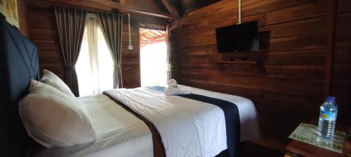 a bedroom with a bed with a tv and a window at Rinjani Hill Hotel in Sembalun Lawang