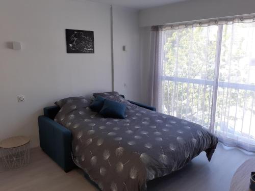 a bed in a bedroom with a large window at Studio Centre - Tout Confort - Tout à pied in La Baule