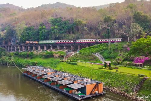 a train on a bridge over a river with barges at Suan Sai Yok Resort in Sai Yok
