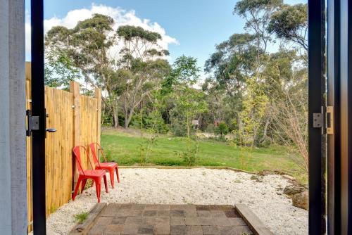 an open door with two red chairs and a fence at Sinofield Edu-Retreat in Leura