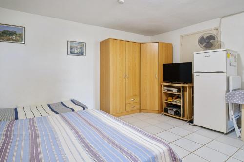 a bedroom with a bed and a tv and a refrigerator at Studio avec vue sur la mer jardin clos et wifi a Saint Paul a 8 km de la plage in Fleurimont