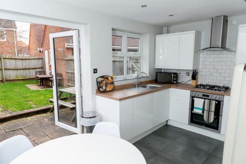 Il dispose d'une terrasse et d'une cuisine équipée d'appareils électroménagers blancs. dans l'établissement A Cosy House Sleeps 7 FREE PARKING Close To The NEC and BHX Airport Three Bedroom House By Be More Homely Serviced Accommodation & Apartments, à Headless Cross