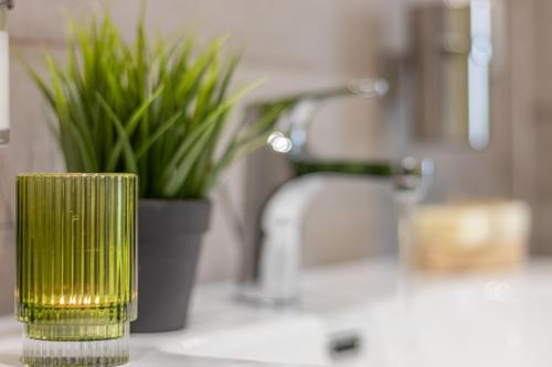 a green candle on a bathroom counter with a plant at Galvani Apartments in Terni