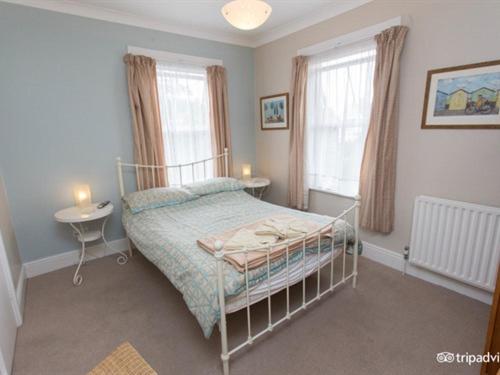 a bedroom with a bed and a table and two windows at The Beeches in Clacton-on-Sea