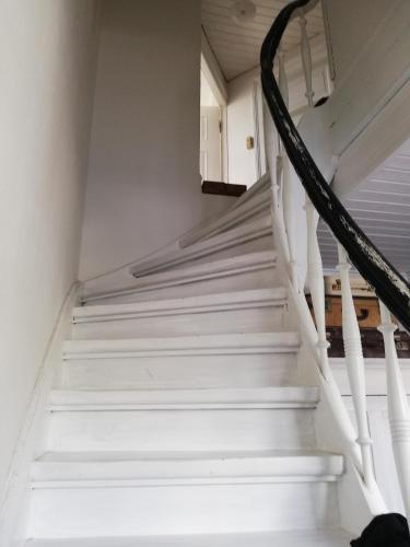 a staircase in a house with white stairs at Tankefuld Living's Horsefarm in Svendborg