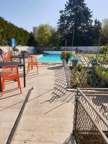 un patio avec une table et des chaises à côté d'une piscine dans l'établissement la maison porte bonheur, à Chantelle
