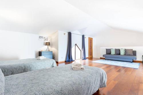 a bedroom with two beds and a blue couch at Baia da Luz - Poolview Loft Aparment in Luz