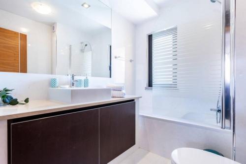 a bathroom with a sink and a tub and a toilet at Baia da Luz - Poolview Loft Aparment in Luz