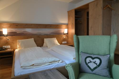 a bed with a green chair in a room at Zum Fally - Landgasthof in Kirchberg am Wechsel