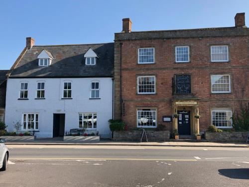 a large brick building on a street with a car parked in front at The Ilchester Arms Hotel, Ilchester Somerset in Ilchester