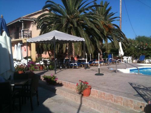 a patio with a table and an umbrella next to a pool at Lord Complex in Agios Georgios