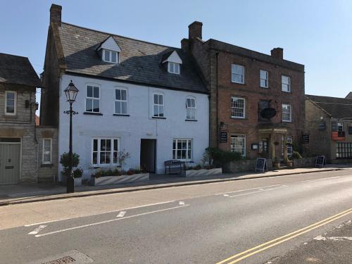 un bâtiment blanc sur le côté d'une rue dans l'établissement The Ilchester Arms Hotel, Ilchester Somerset, à Ilchester