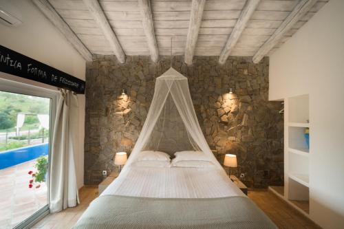 Cama en habitación con pared de piedra en Monte Gois Country House e Spa en Curvatos