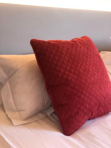 a red pillow on a bed with two white pillows at Hotel Donibane Saint-Jean-de-Luz in Saint-Jean-de-Luz