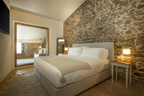 a bedroom with a large bed and a stone wall at Hotel Mas del Sol in Vall-Llobrega