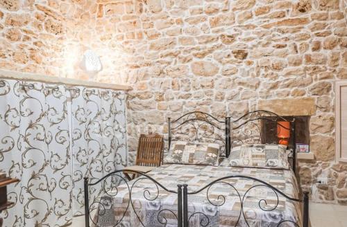 a bedroom with a bed and a stone wall at i Caseddhi di Santo e Totò in Torre Suda