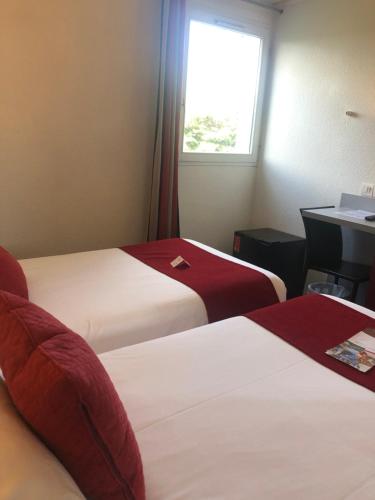 a hotel room with two beds and a window at Hotel Donibane Saint-Jean-de-Luz in Saint-Jean-de-Luz