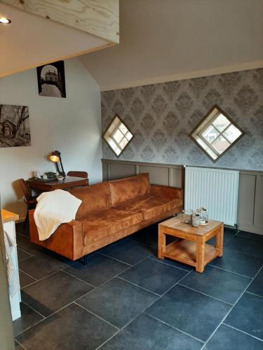 ein Wohnzimmer mit einem braunen Sofa und einem Tisch in der Unterkunft Appartementen Hoek 2 in Baflo