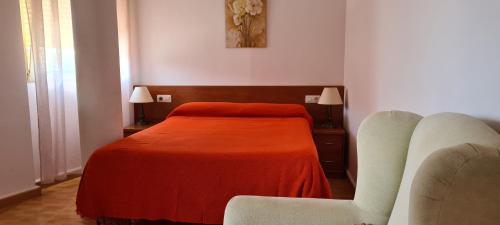 ein Schlafzimmer mit einem Bett mit einer orangefarbenen Decke in der Unterkunft Apartamentos Bellavista in Puerto de Mazarrón