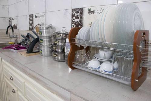 a dish rack with plates and cups on a kitchen counter at ODG Cotonou - Résidences Océan De Grâce in Cotonou