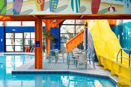 una piscina con tobogán, mesas y sillas junto a una piscina en Camping Pods, Dovercourt Holiday Park, en Harwich