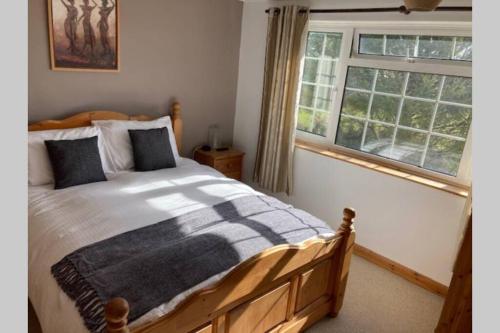 a bedroom with a wooden bed and a window at ** Beautiful Scenery - Cyclists & Walkers Dream ** Log Burner ** Peaceful Hamlet ** in Redruth