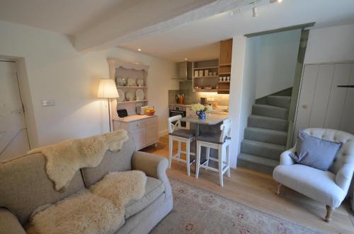 a living room with a couch and a chair and a kitchen at Wrenscott in Chagford