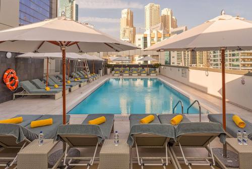 a swimming pool with chairs and umbrellas at Wyndham Dubai Marina in Dubai